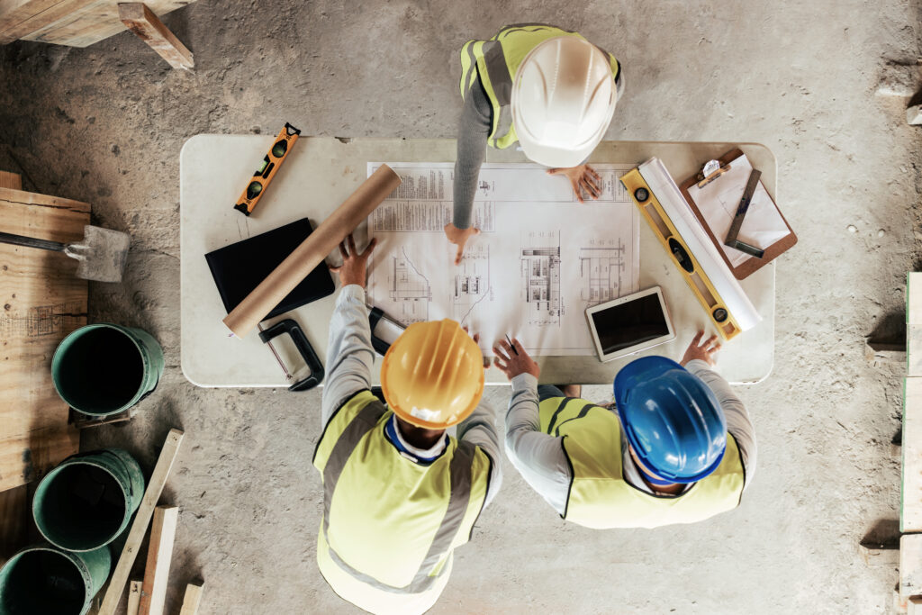 Top view, construction workers or blueprint planning in house, home or office building in real estate, property or architecture innovation Men, engineering woman or construction site people or ideas